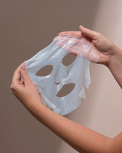 Person holding a clear silicone mask with cutouts against a neutral background