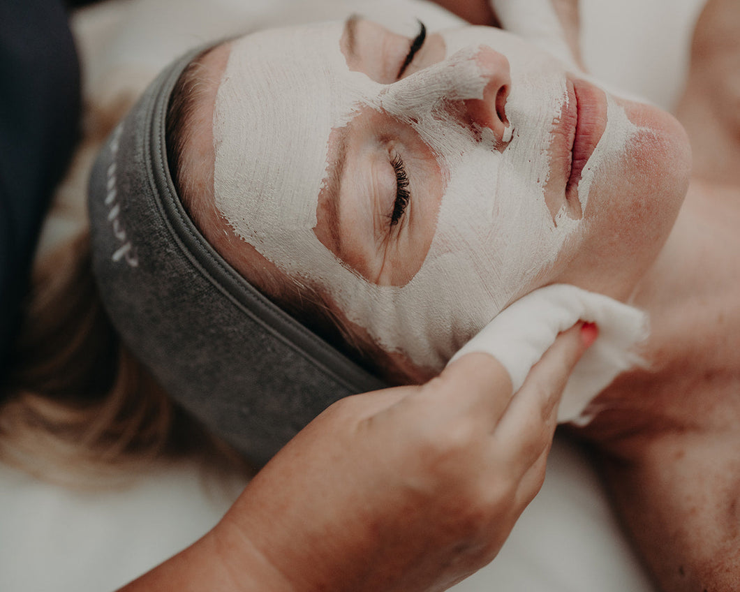 Person receiving a facial mask treatment with a close-up of the face.